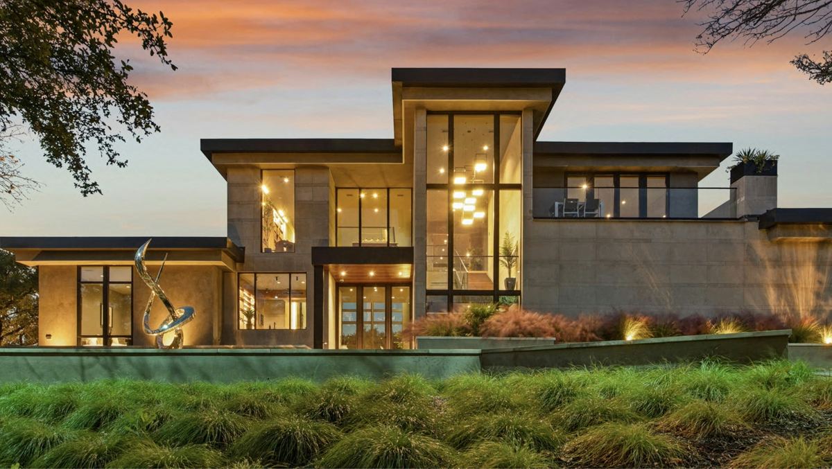 Contemporary stone and glass house lit at dusk